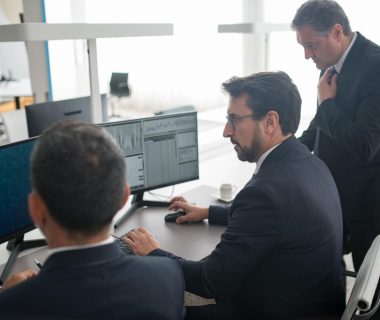Business professionals analyzing data on computer monitors, reflecting the role of ai security in investment decisions.