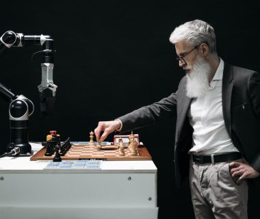 Man strategizing chess moves with a robotic arm, reflecting the interplay between human and ai agents in tech oversight discussions.