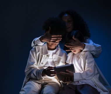 An adult obscuring children's faces while they engage with a tablet, highlighting user privacy concerns in AI agents.