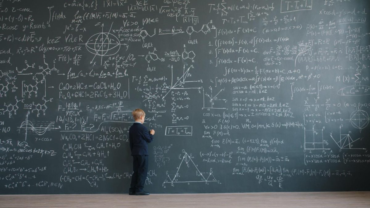A young child in a suit demonstrates problem-solving on a chalkboard, symbolizing human intuition in math as AI agents advance.